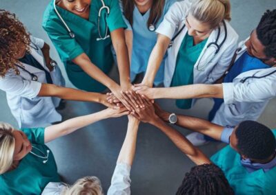 aerial view of a team of doctors putting their hands in the middle of a team huddle