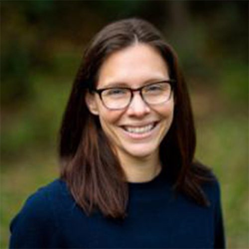 Smiling headshot, wearing glasses and a dark blue top.