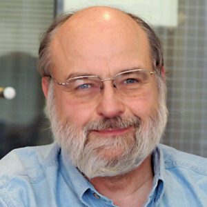 Headshot, smiling, wearing glasses, a beard and a collared shirt.
