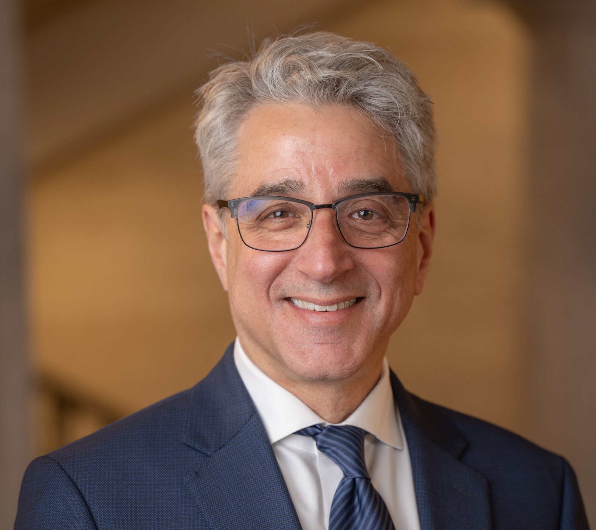 OVPR Staff Headshots March 10, 2025. headshot of Arthur Lupia wearing a blue suit and glasses standing in Ruthven's rotunda