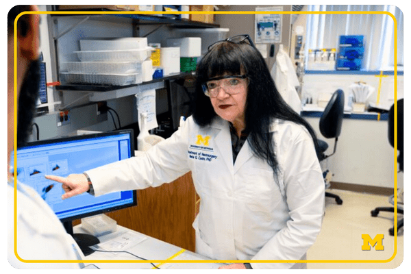 photo of Maria Castro talking with a lab staff member, gesturing at a computer