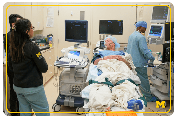 photo of a patient in a hospital bed, wearing a cap and scrubs, speaking with medical staff in a hospital room