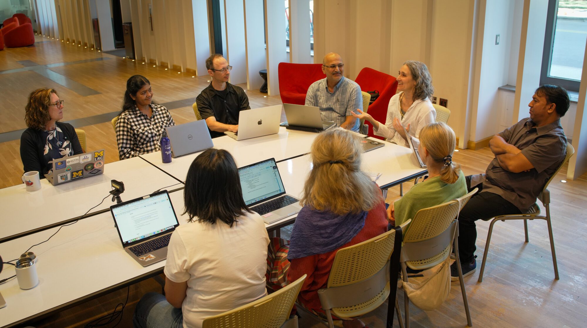 Dr. Christi Merrill and her colleagues Group of people sit in a classroom around tables with laptops, engaged in active discussion and collaborative work