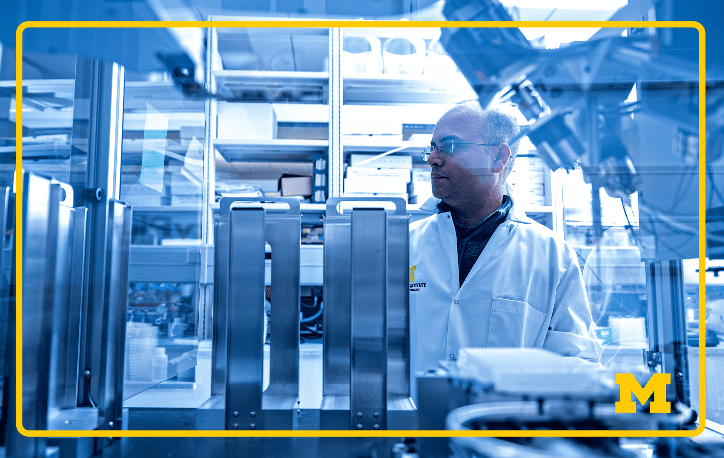 Scientist stands among advanced robotics and scientific instruments in a high-tech laboratory, shelves of equipment in background.