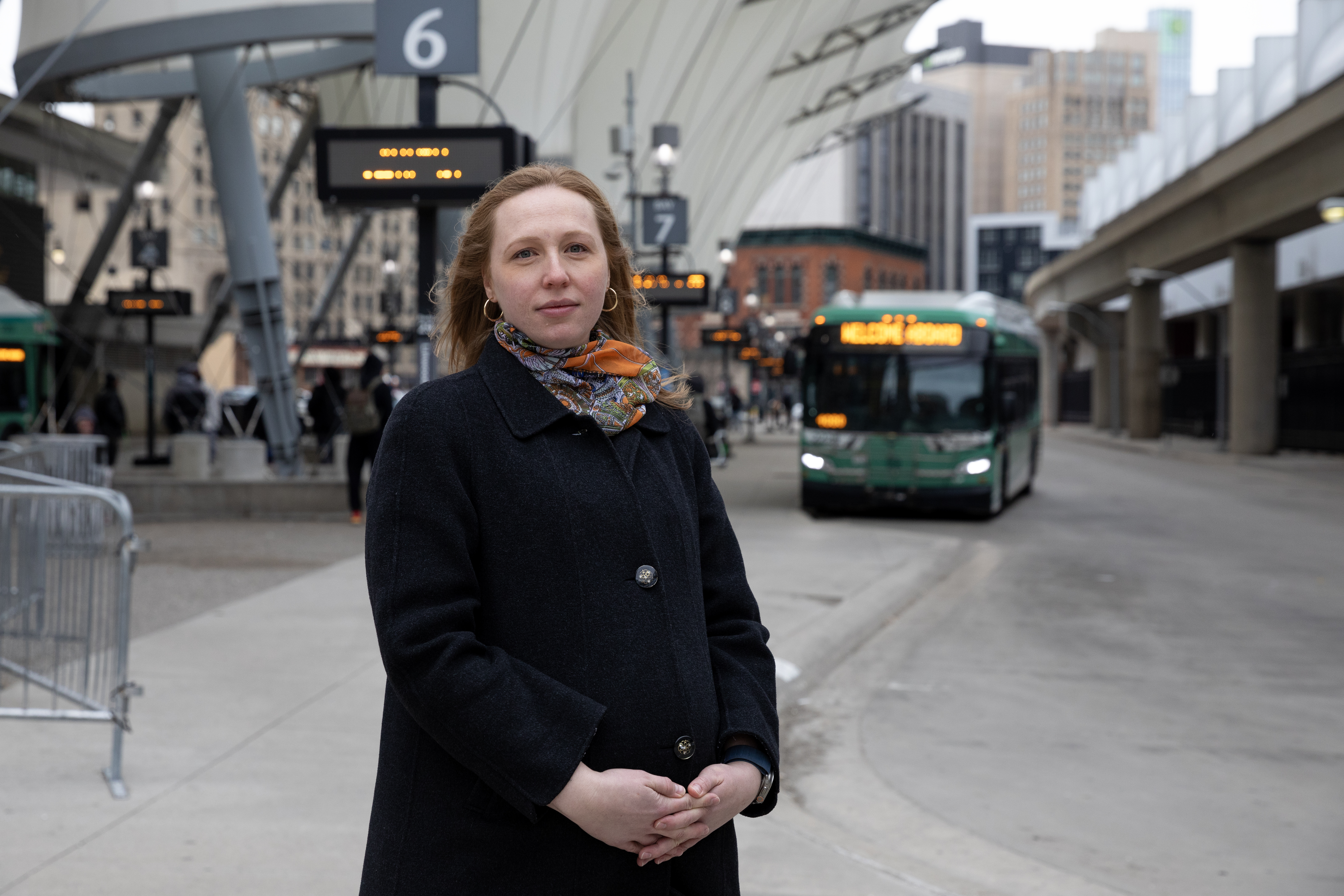 Erica Twardzik stands in Detroit in front of a bus station.