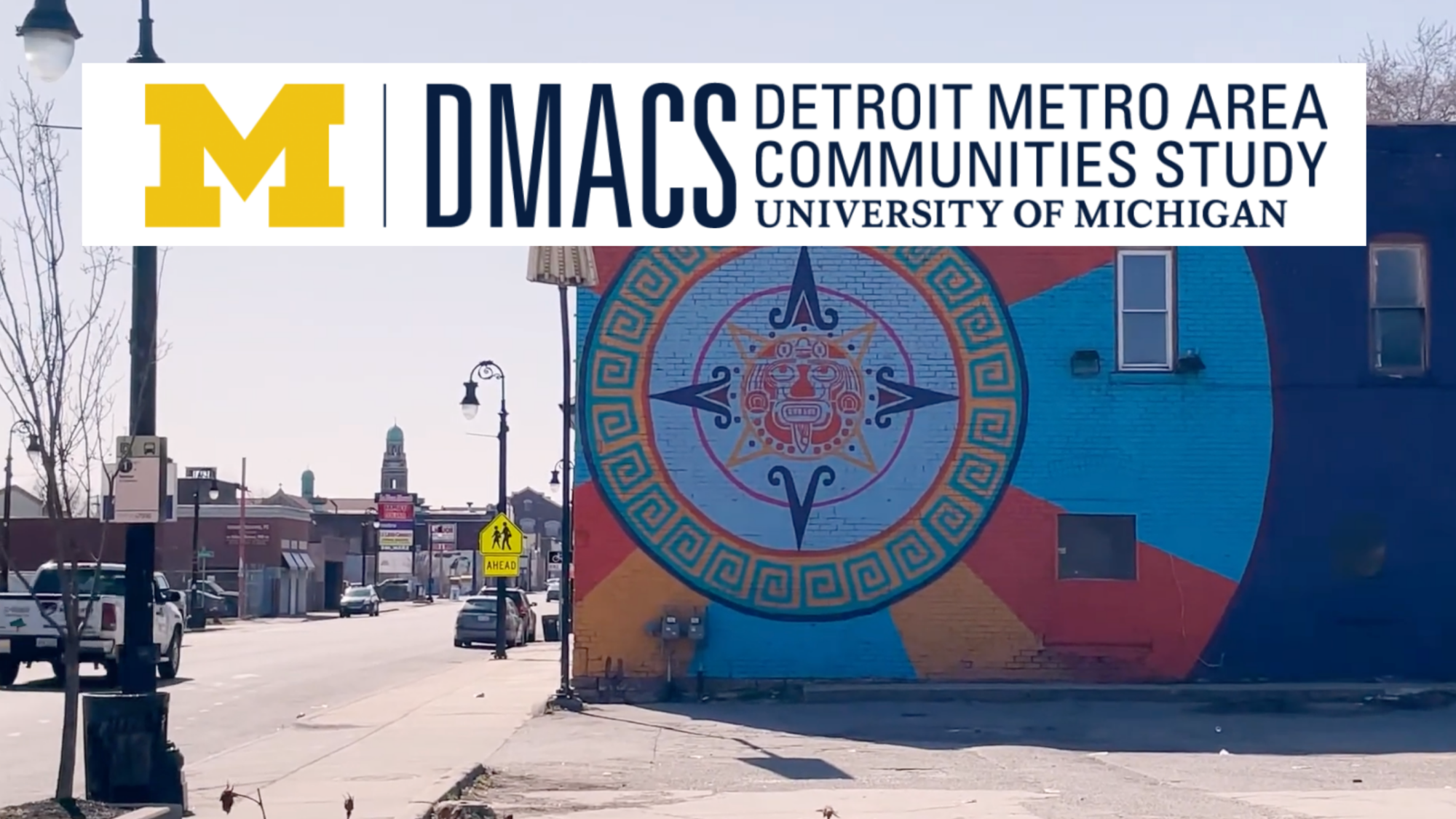 A car drives through an intersection in an urban area on a cloudy day, with steam rising from a manhole and city buildings, trees, and streetlights in the background. A large sign overlays the image, reading “A report from the U-M Detroit Metro Area Communities Study (DMACS)."