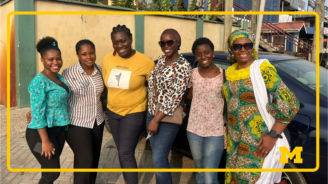 Research collaborators and partners, left to right: Amanda Owusua Omane, Adwoa Safo, Sylvia Akpene Takyi, Fayizatu Dawud, Abena Boatemaa Wadee, and Hamdaratu Dauda. Six people stand closely together posing outdoors in front of a parked dark car and a tan wall. They wear a mix of casual tops and patterned outfits; the person on the far right wears a green-and-yellow patterned outfit with a matching headwrap and a white drape.