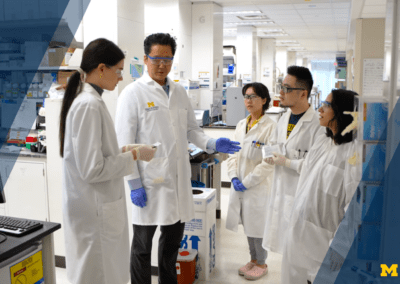 photo of James Moon speaking with a group of students in his lab