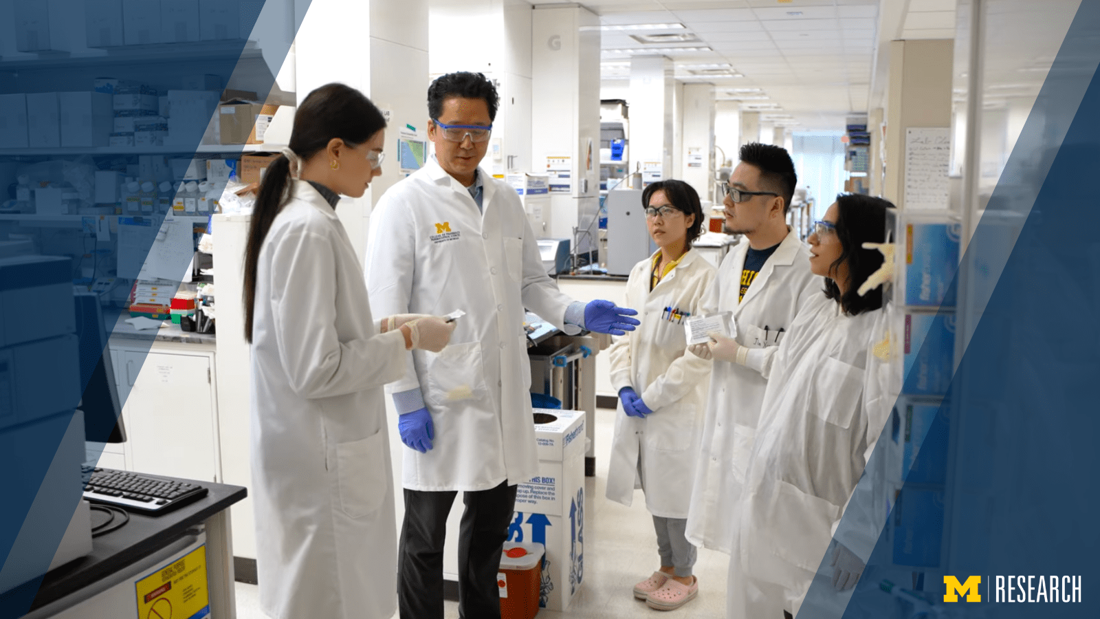 photo of James Moon speaking with a group of students in his lab