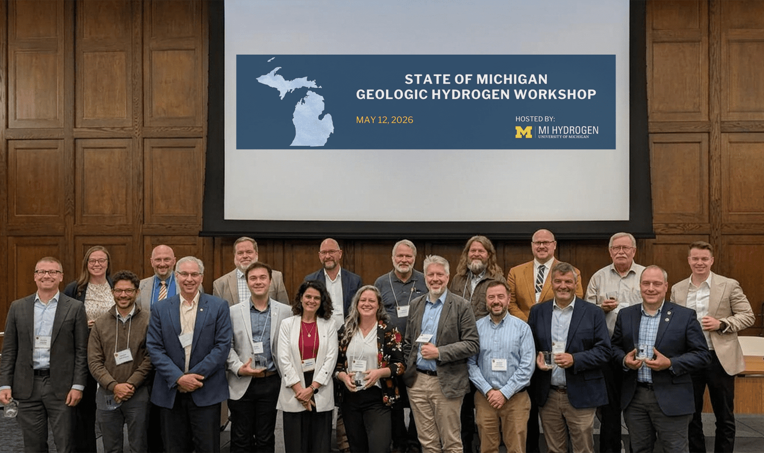 A group poses in front of a screen that reads MI Hydrogen Geologic Workshp