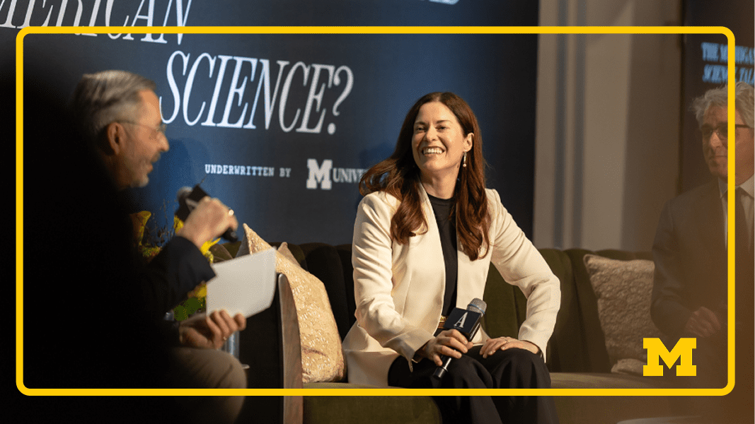Panelists discuss science onstage, with a woman holding a microphone at center.