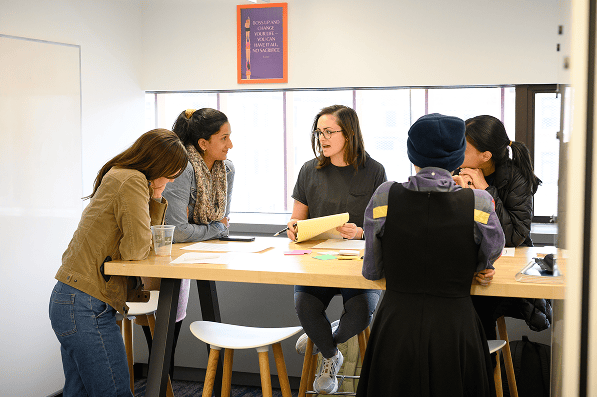 MPHOTO_RSB_DesignThinkingWrksp Students collaborate around a table during a discussion in a bright classroom.